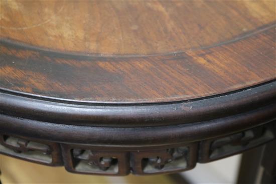 A Chinese carved hardwood oval pedestal table with pierced frieze and peripheral stretcher W.87cm